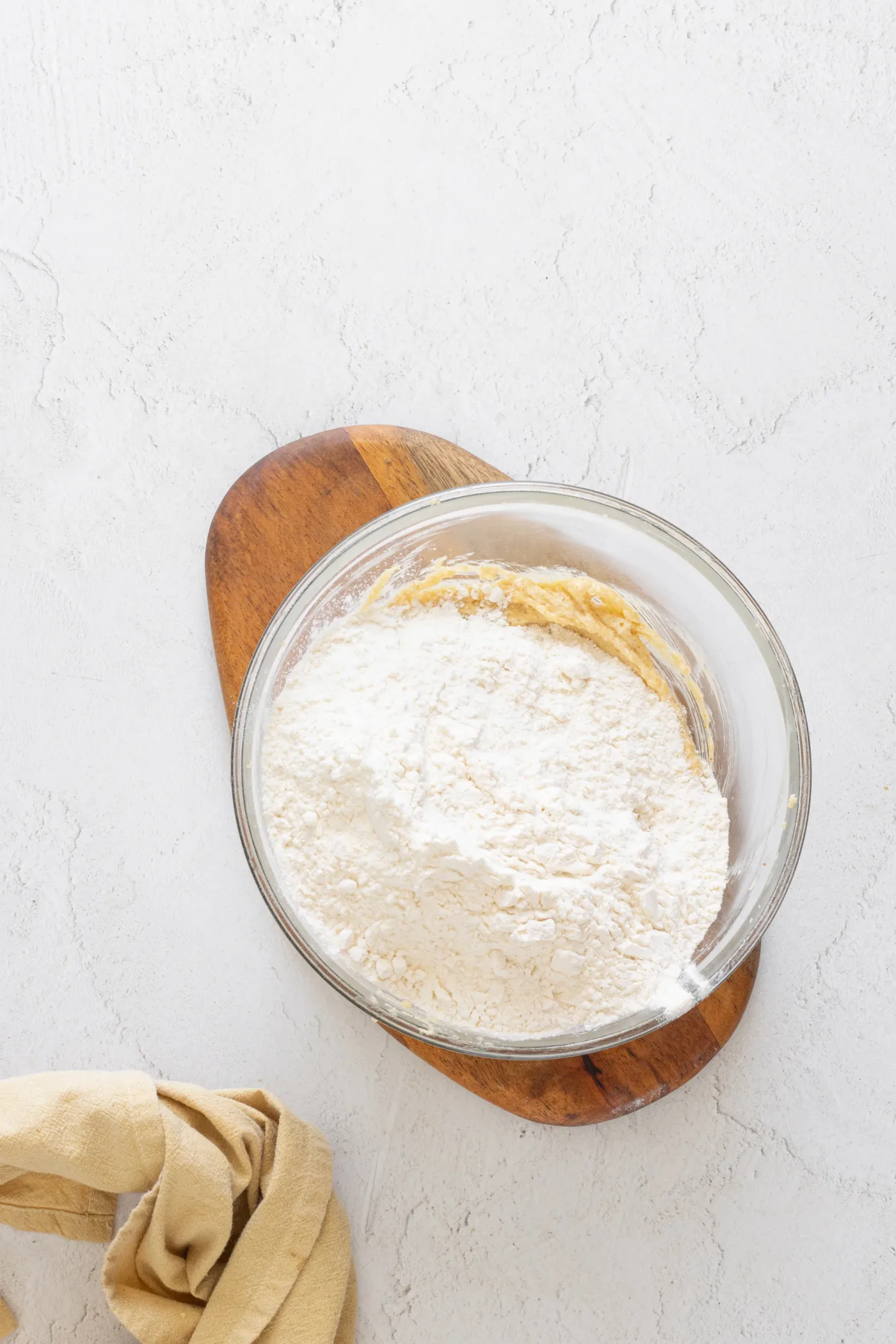 Flour added to the brown butter cookie mixture in a glass bowl